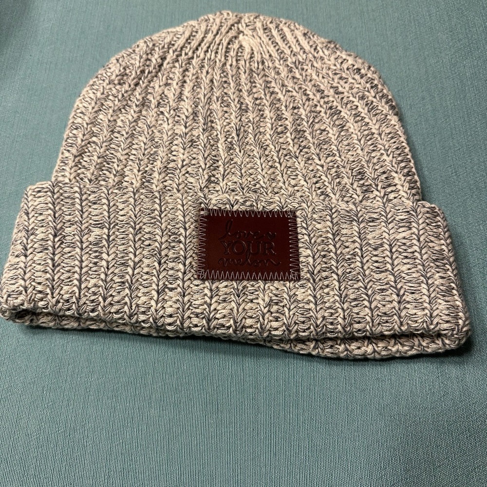 Light gray and white Love Your Melon cuffed beanie with brown patch